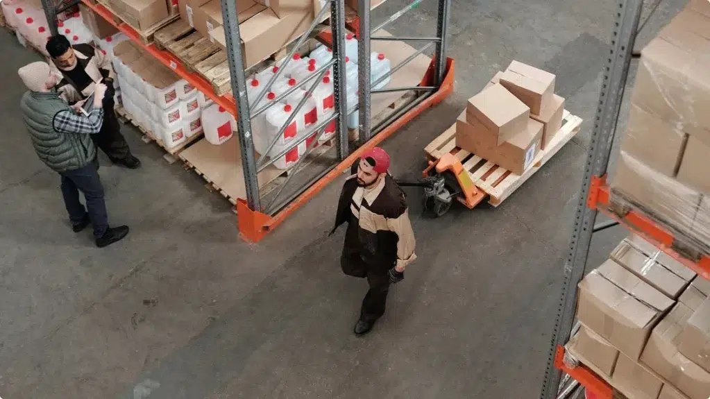 3 hommes travaillent dans les allées d'un entrepôt de stockage