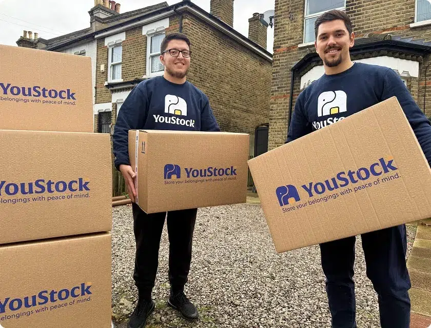 Two YouStock movers, each holding a moving box in their hands