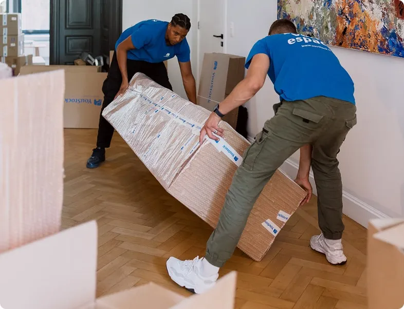 Two movers tilting a large piece of furniture that has been protected and packed