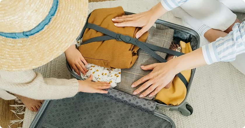 A mother and daughter fill a suitcase with clothes.