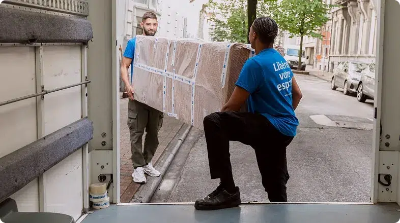 Deux déménageurs YouStock portent un meuble emballé et protégé