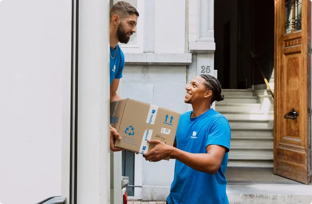 Two YouStock movers passing a moving box at the back of a truck