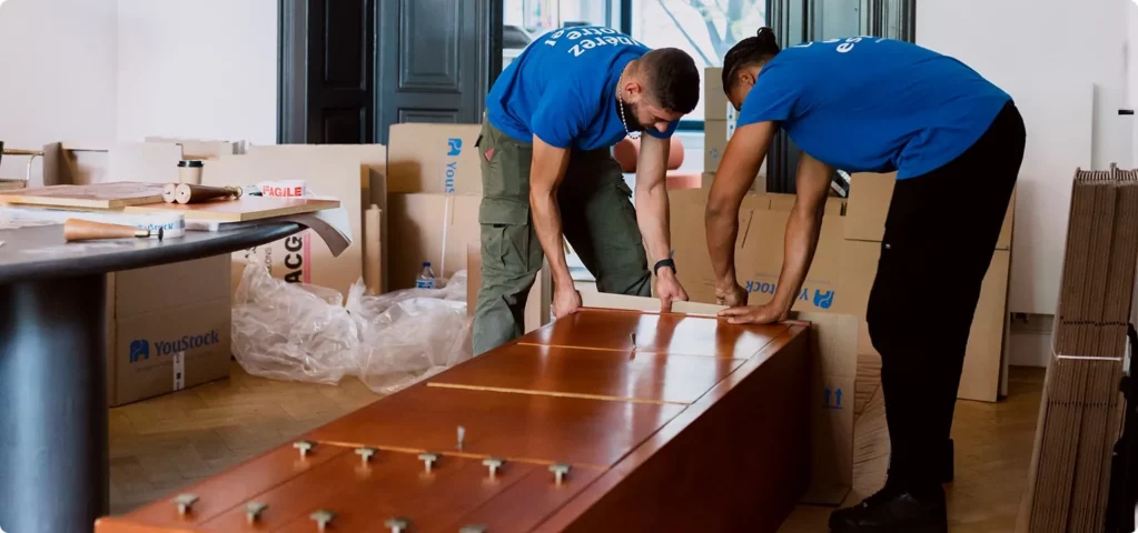 Two YouStock movers protect a piece of furniture for moving.