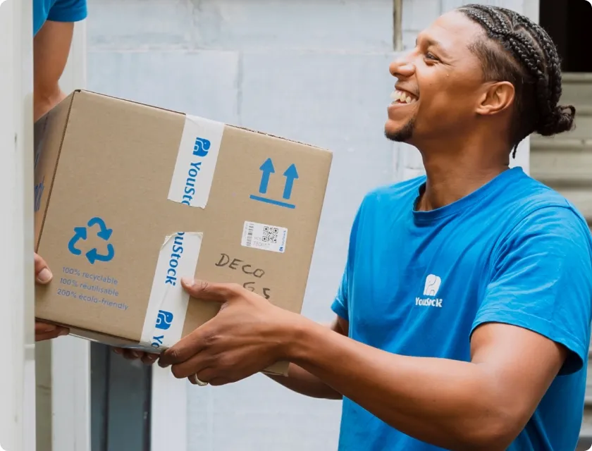 Déménageur YouStock soulevant un carton de déménagement recyclé