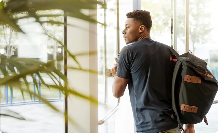 Un étudiant pousse une porte vitrée pour sortir