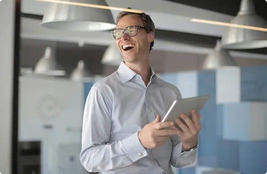 Homme en train de tenir une tablette se tient debout, avec un grand sourire