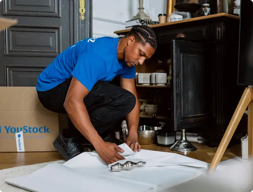 Un déménageur YouStock emballe un bibelot soigneusement pour le déménager.