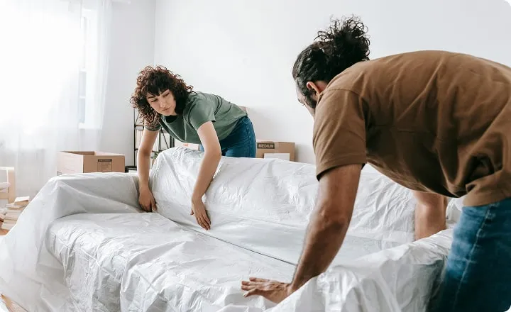 Un couple pose une bâche de protection sur un canapé
