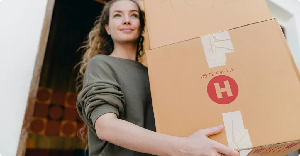 Jeune femme portant deux cartons empilés