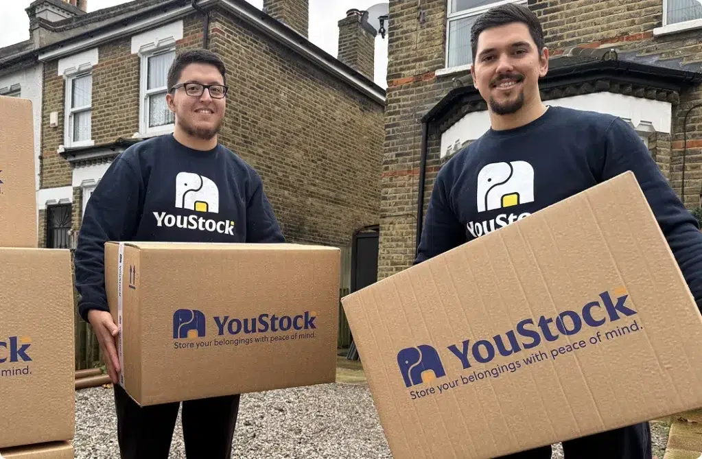 Two YouStock movers each carry a YouStock branded cardboard box - Store your belongings with peace of mind.