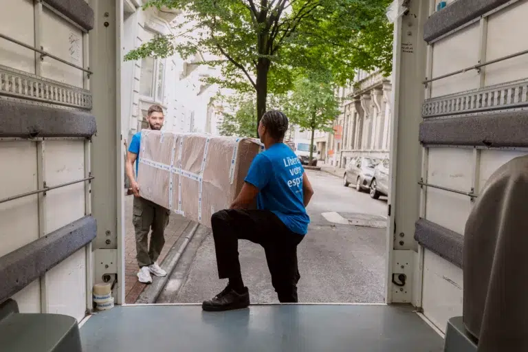 déménageurs YouStock qui portent un grand carton