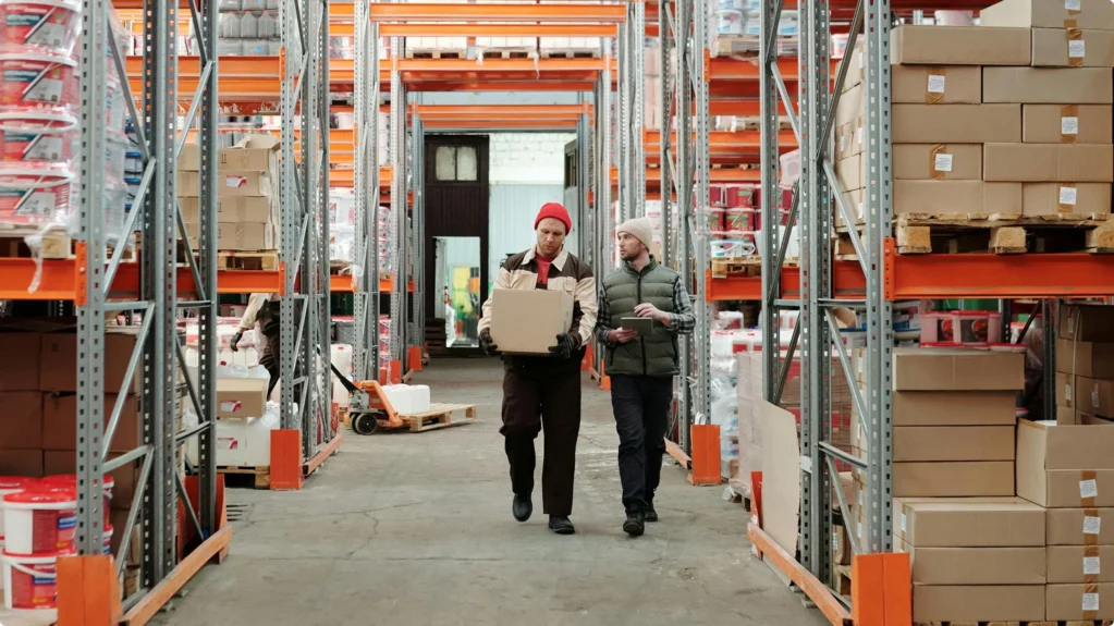 Two logistics workers working in the middle of an aisle in a warehouse