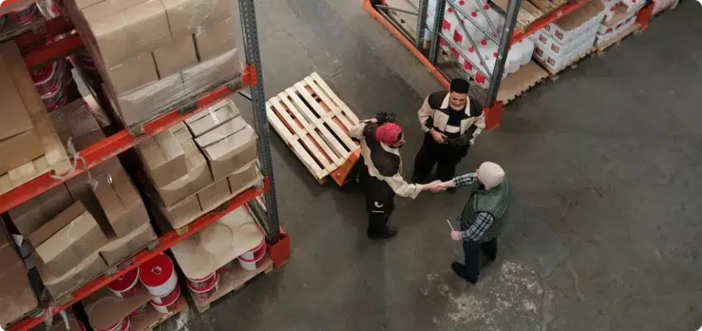 Three logistics specialists gathered in the middle of an aisle in a warehouse