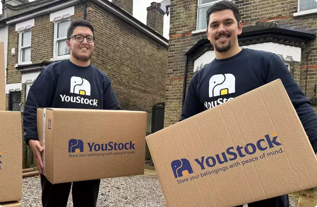 Two YouStock movers each carry a YouStock branded cardboard box - Store your belongings with peace of mind.