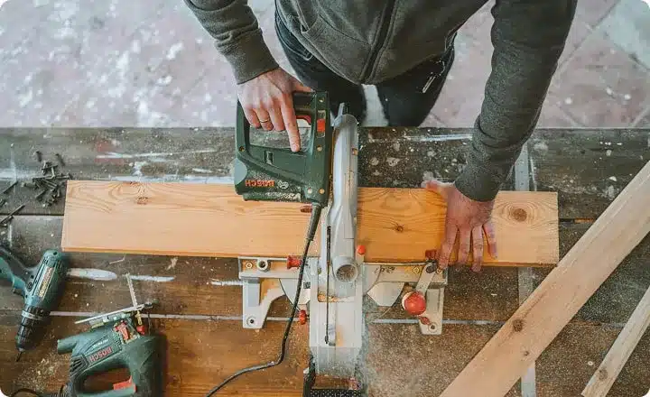 Un homme scie une planche de bois