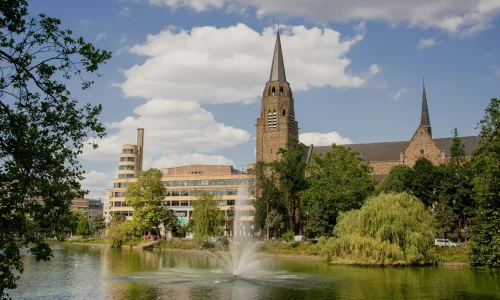 A tree-lined urban landscape with a church in the background