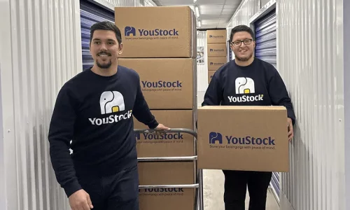 Two YouStock removal men transport storage boxes.