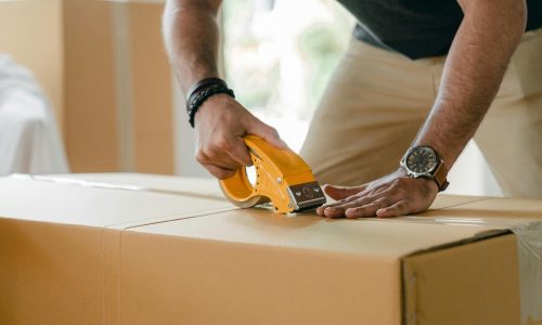 Close-up of a man's hands taping a moving box